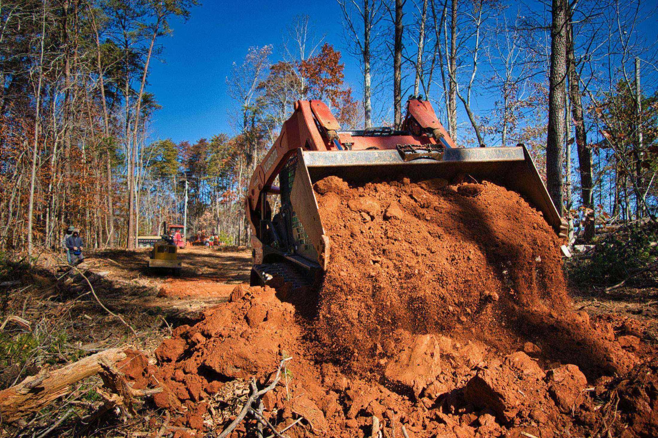 Skid steer loader moving dirt on a residential lot